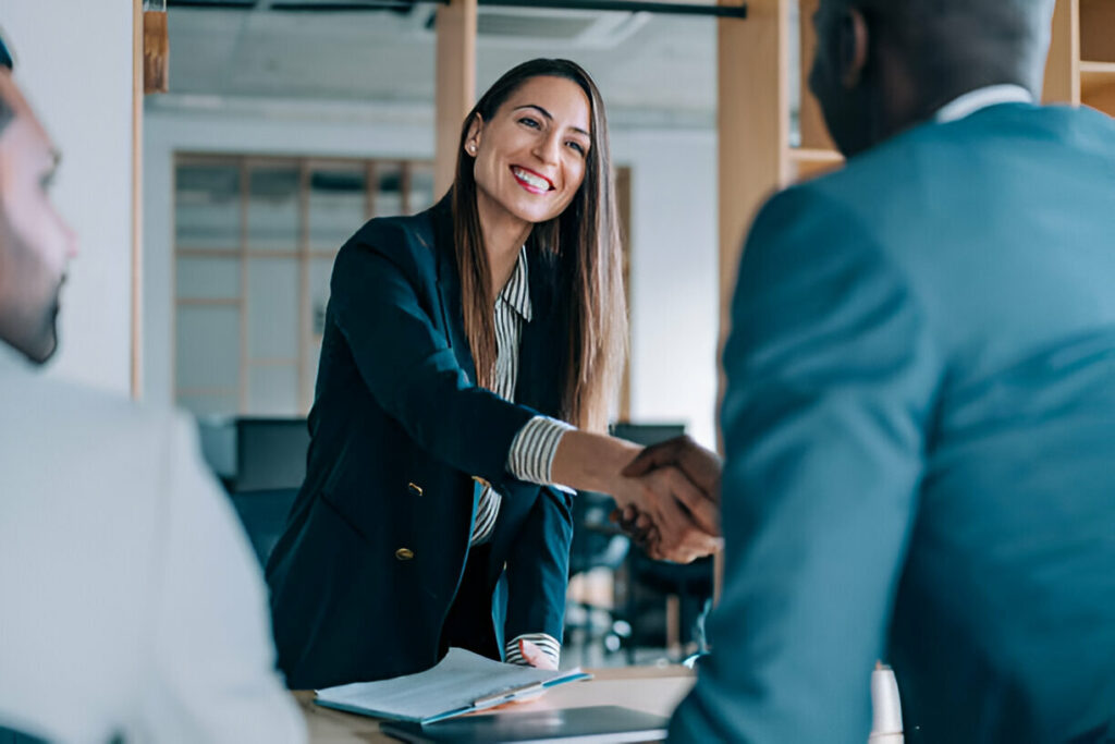 Businesswoman shaking hands with candidate in a Poached Jobs scenario